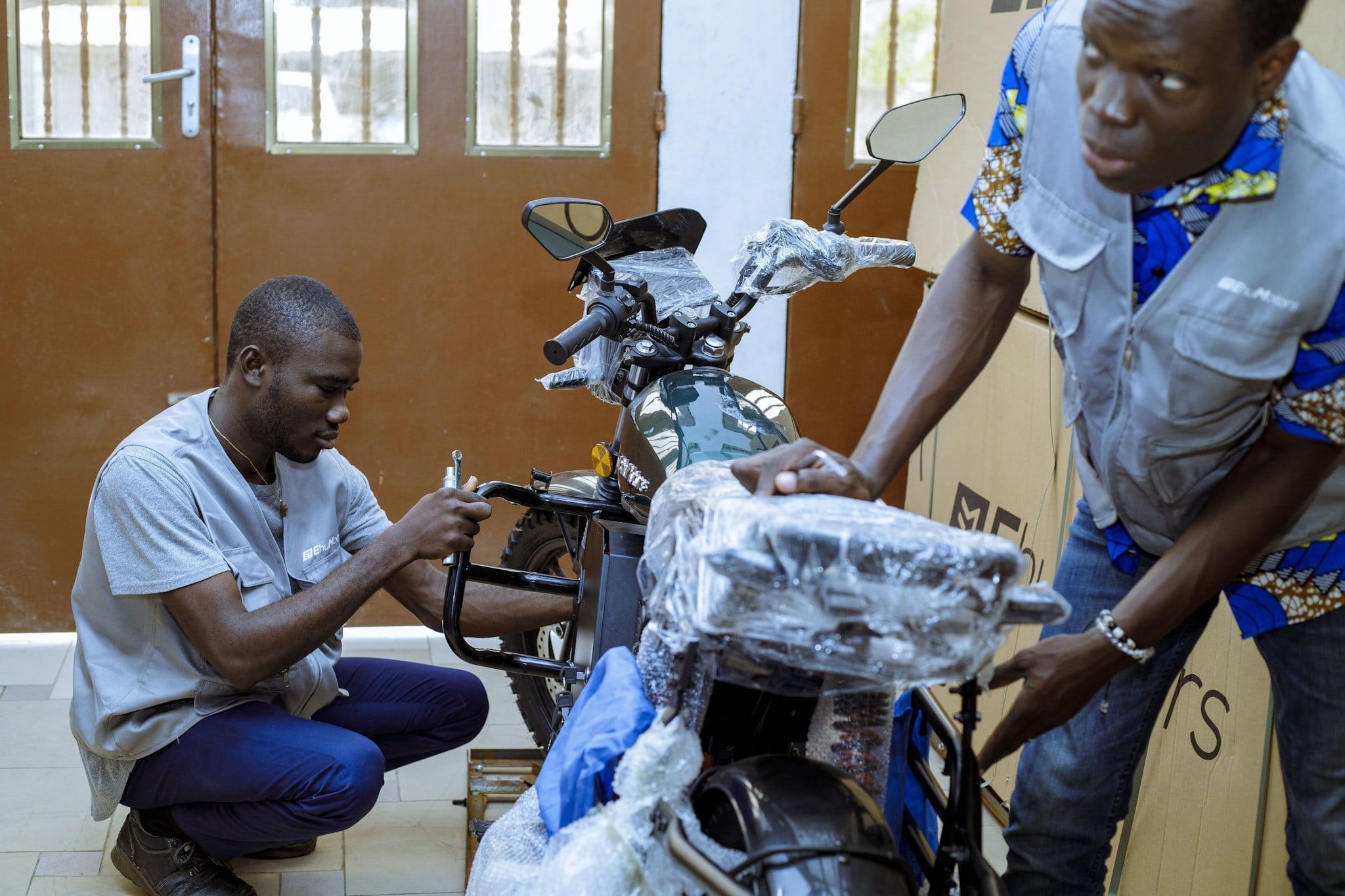 Two Ehu technicians prepare a new motorcycle at the Cotonou workshop.