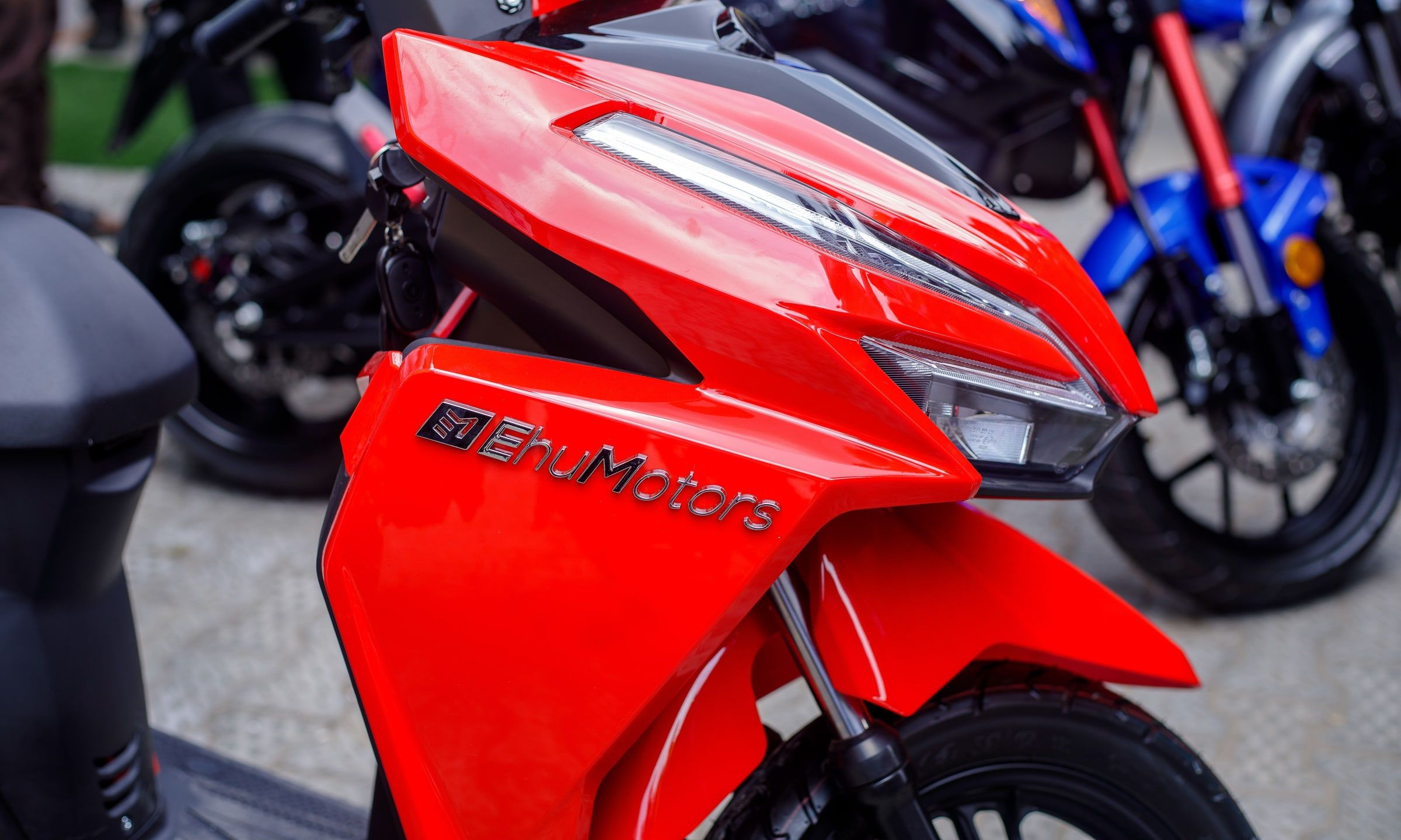 The front of a red Ehu electric scooter, with the Ehu Motors logo on the fairing.