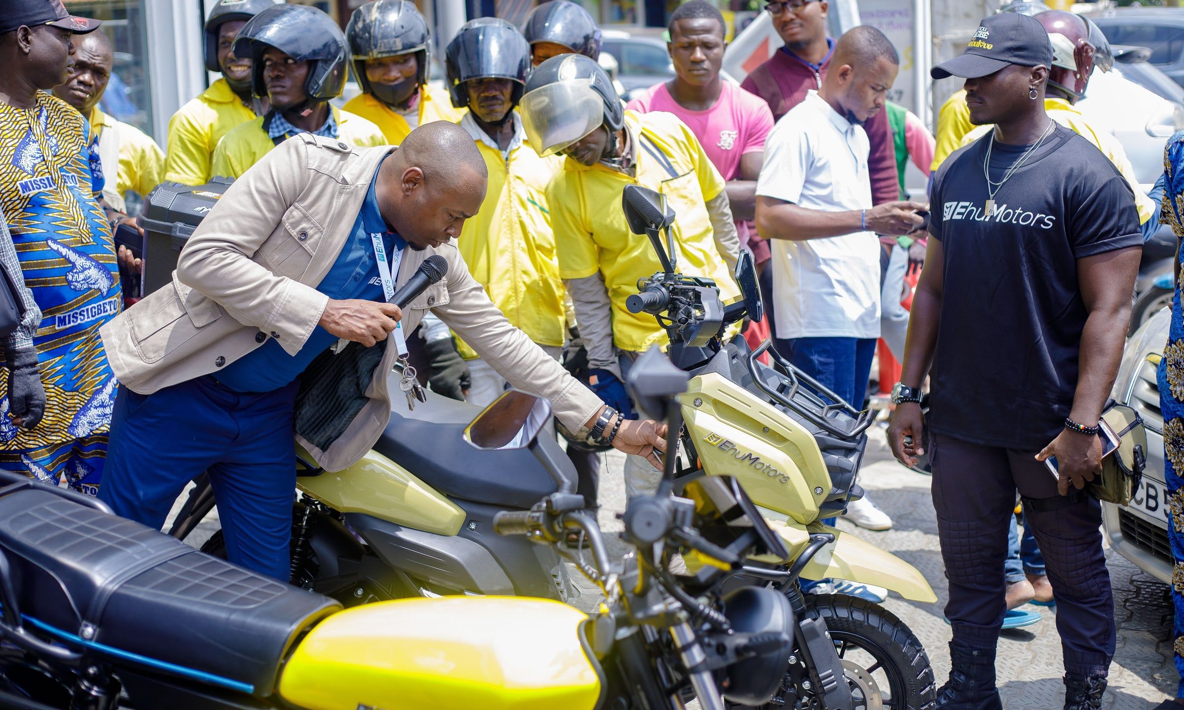 Des conducteurs examinent un Djabi jaune, le scooter de livraison Ehu.
