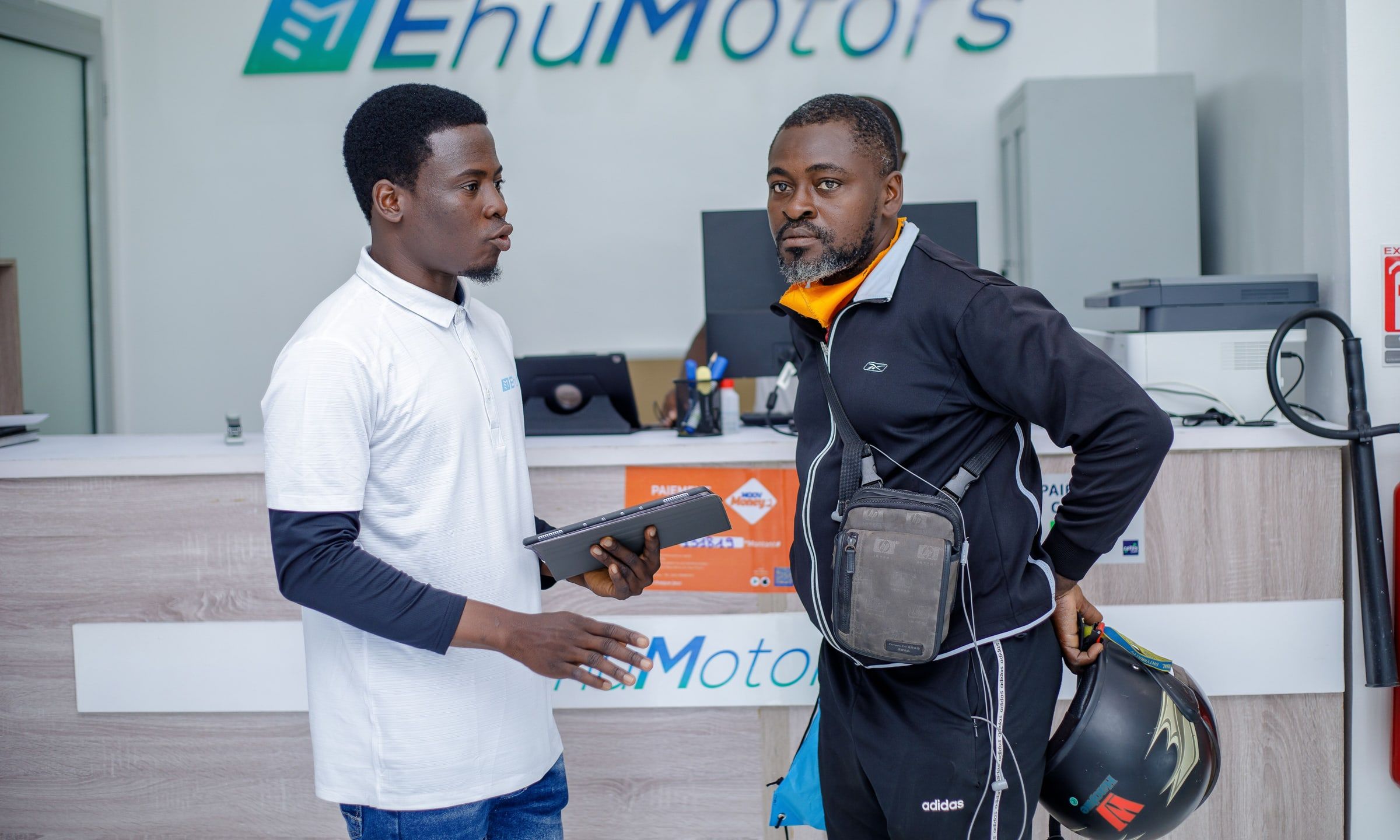 At the showroom counter, an Ehu advisor answers a customer, tablet in hand.